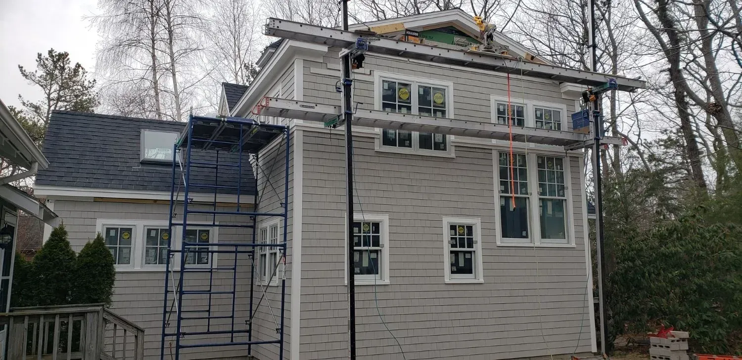 A house with a ladder on the side of it is being remodeled.