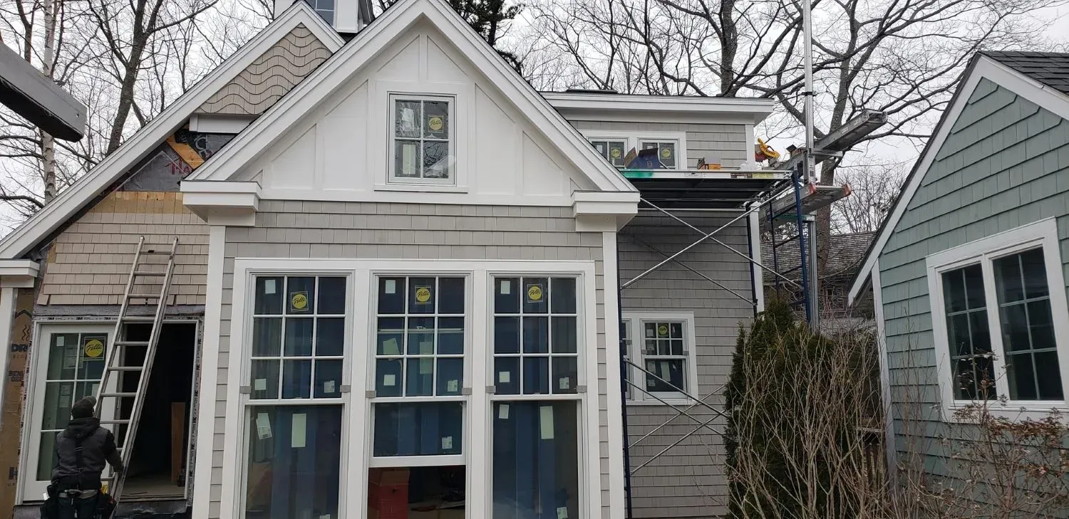 A small house with a lot of windows is being remodeled.