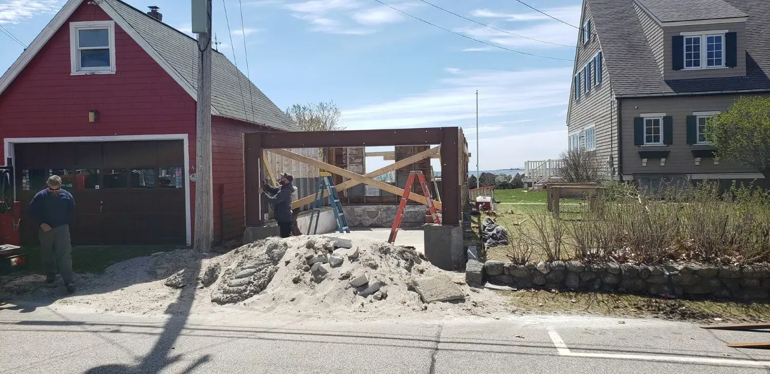 A red garage is being built next to a white house.