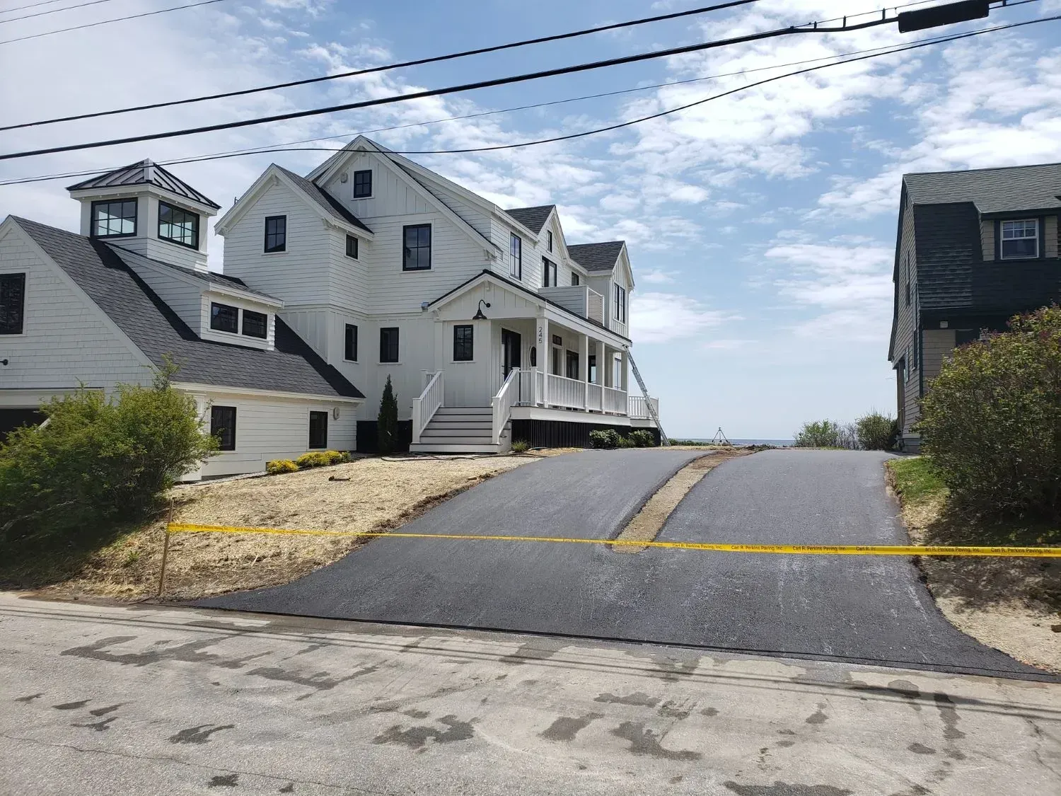 A large white house is sitting on top of a hill next to a road.