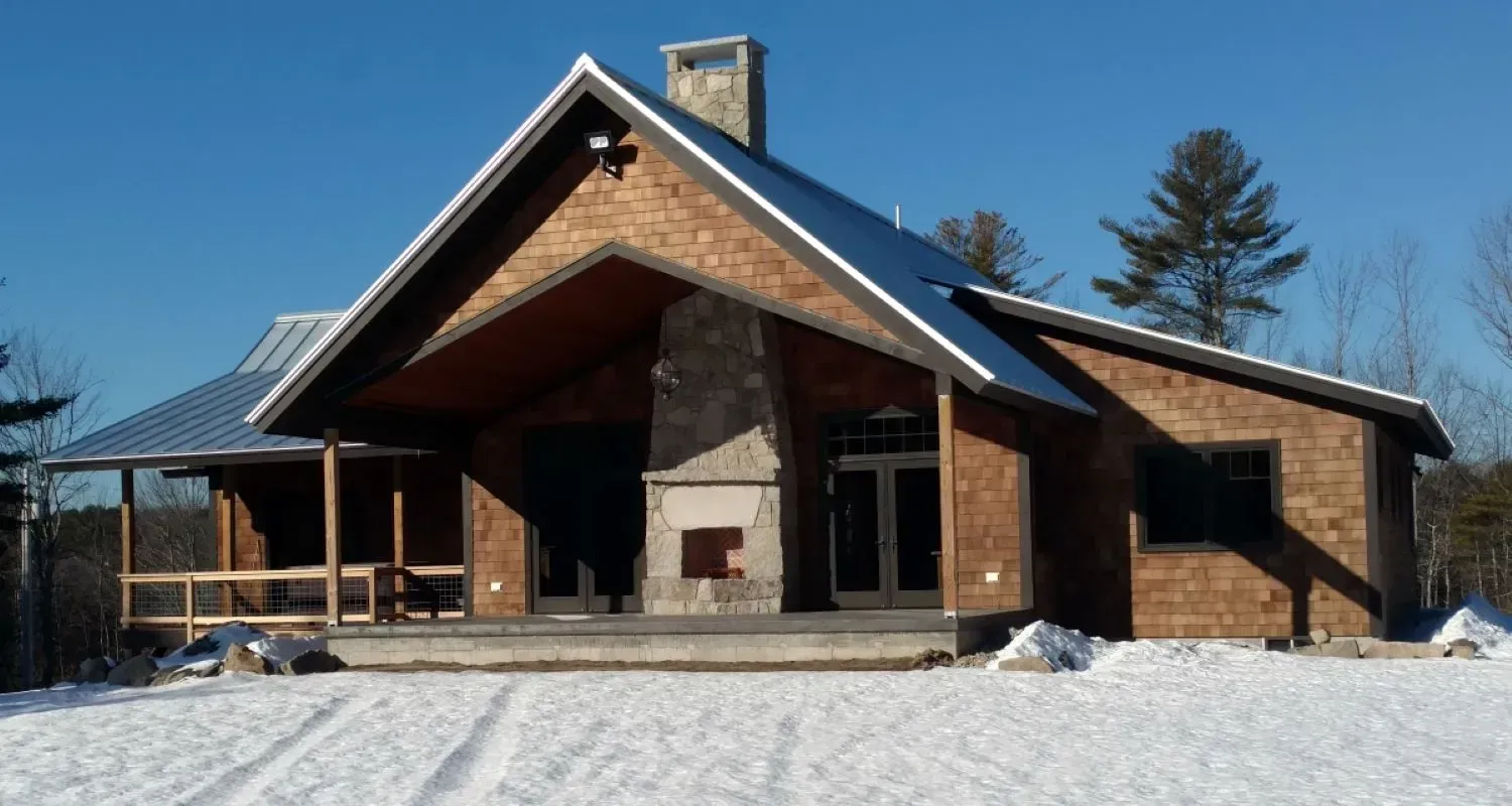 A house with a porch and a chimney in the snow