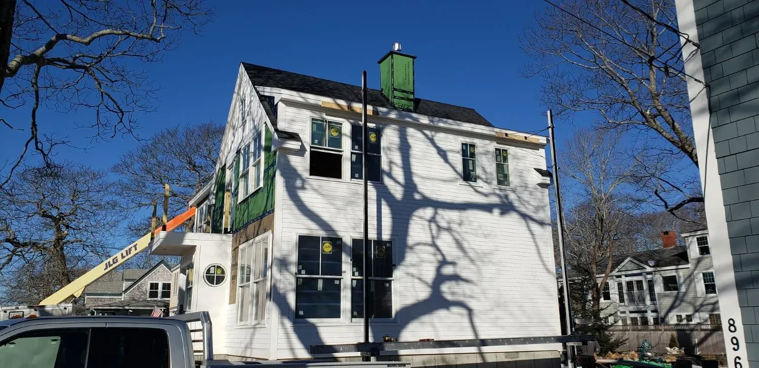 A white house is being remodeled on a sunny day.
