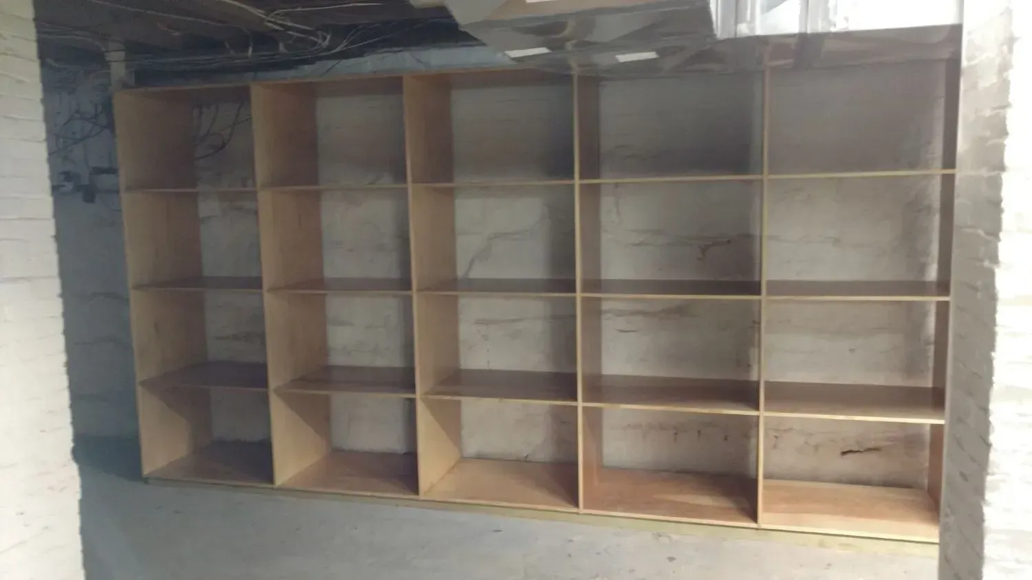 A row of wooden shelves against a white wall