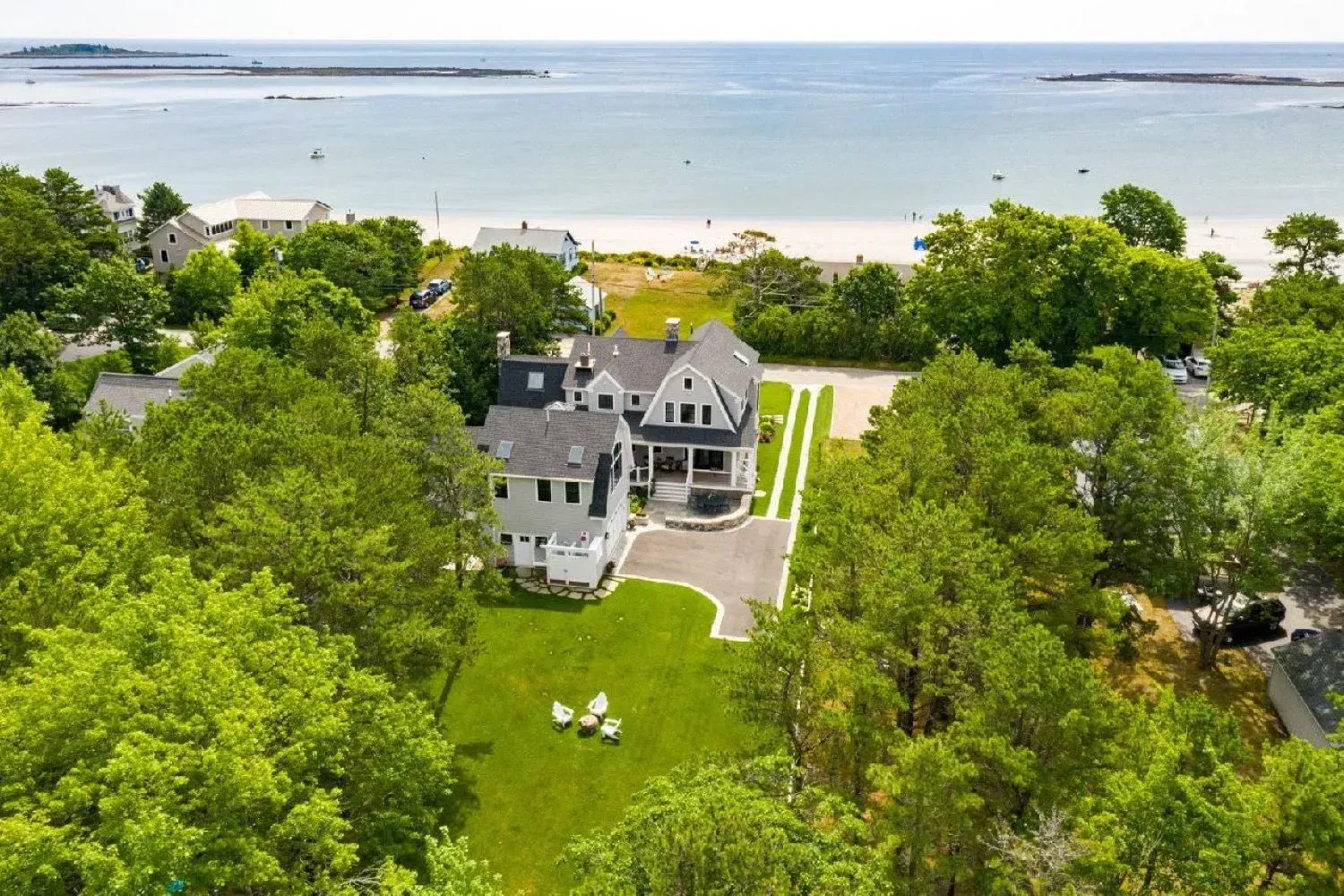 An aerial view of a large house surrounded by trees next to the ocean.
