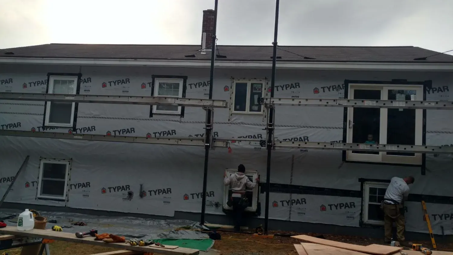 Two men are working on the side of a house.