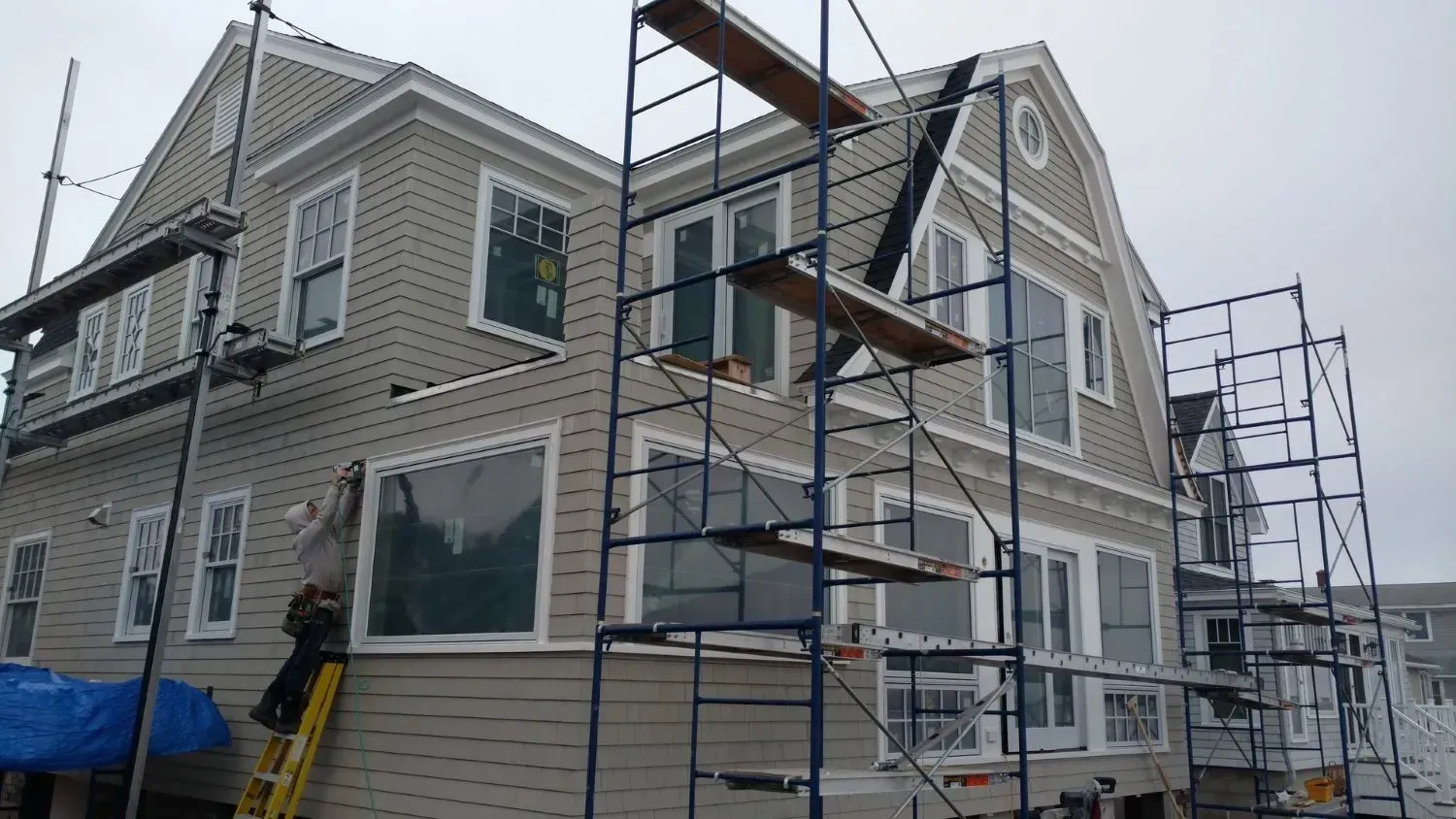 A large house is being painted with scaffolding around it.