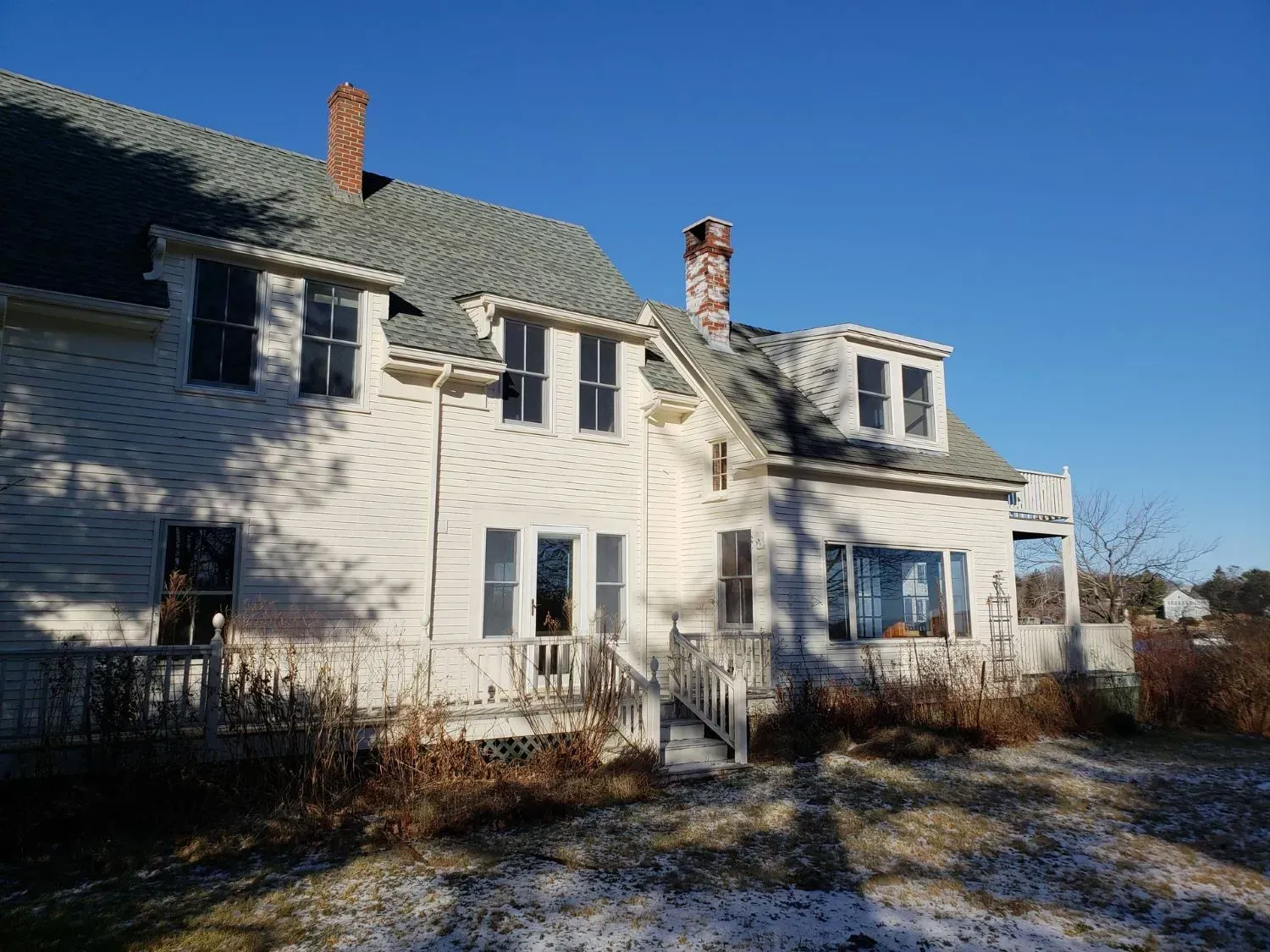 A white house with a gray roof and a chimney