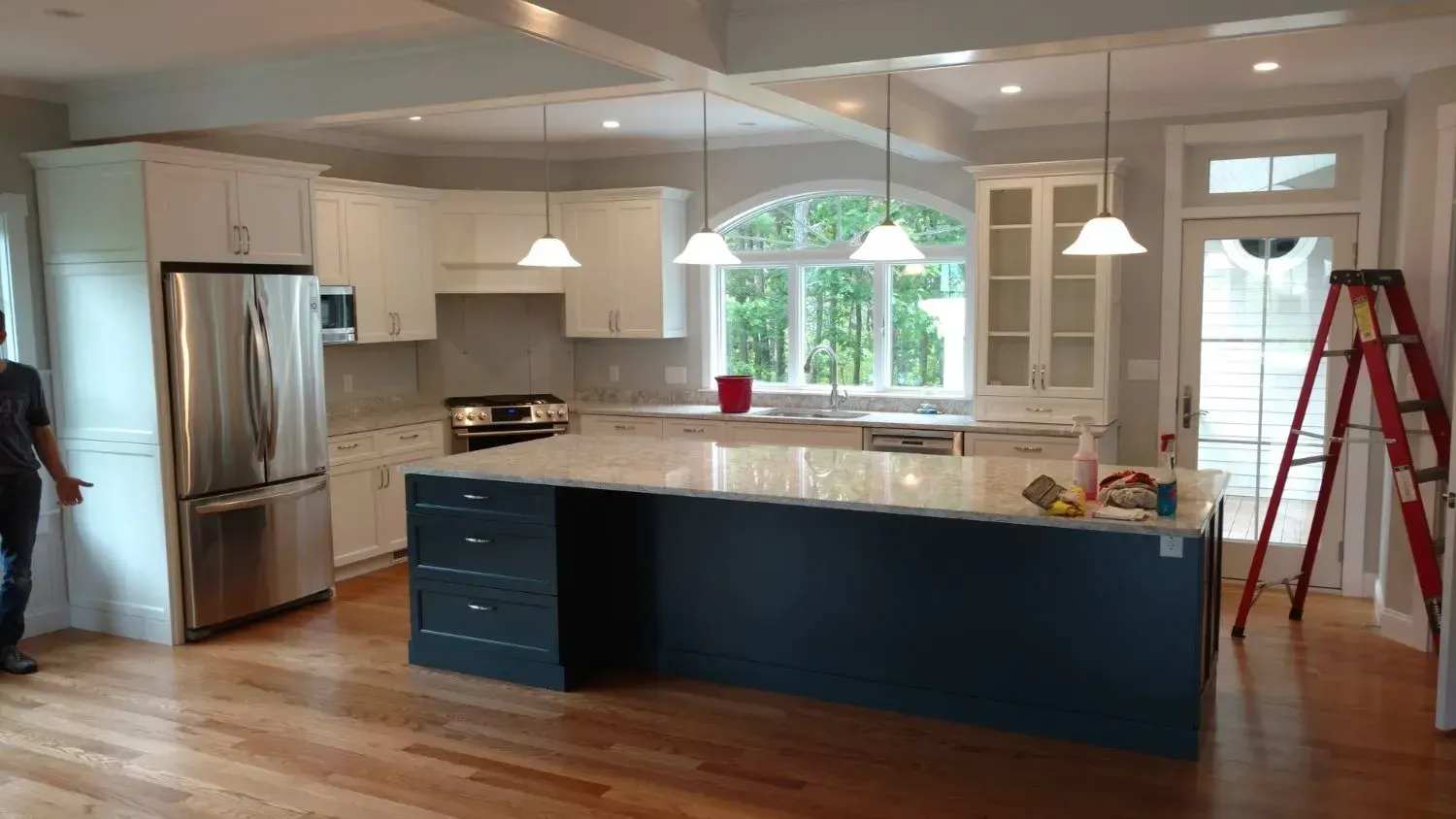 A man is standing in a kitchen with a ladder.