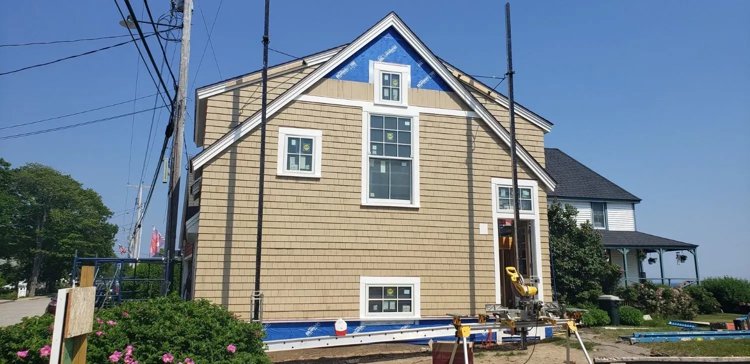 A large house with a blue roof is being remodeled.
