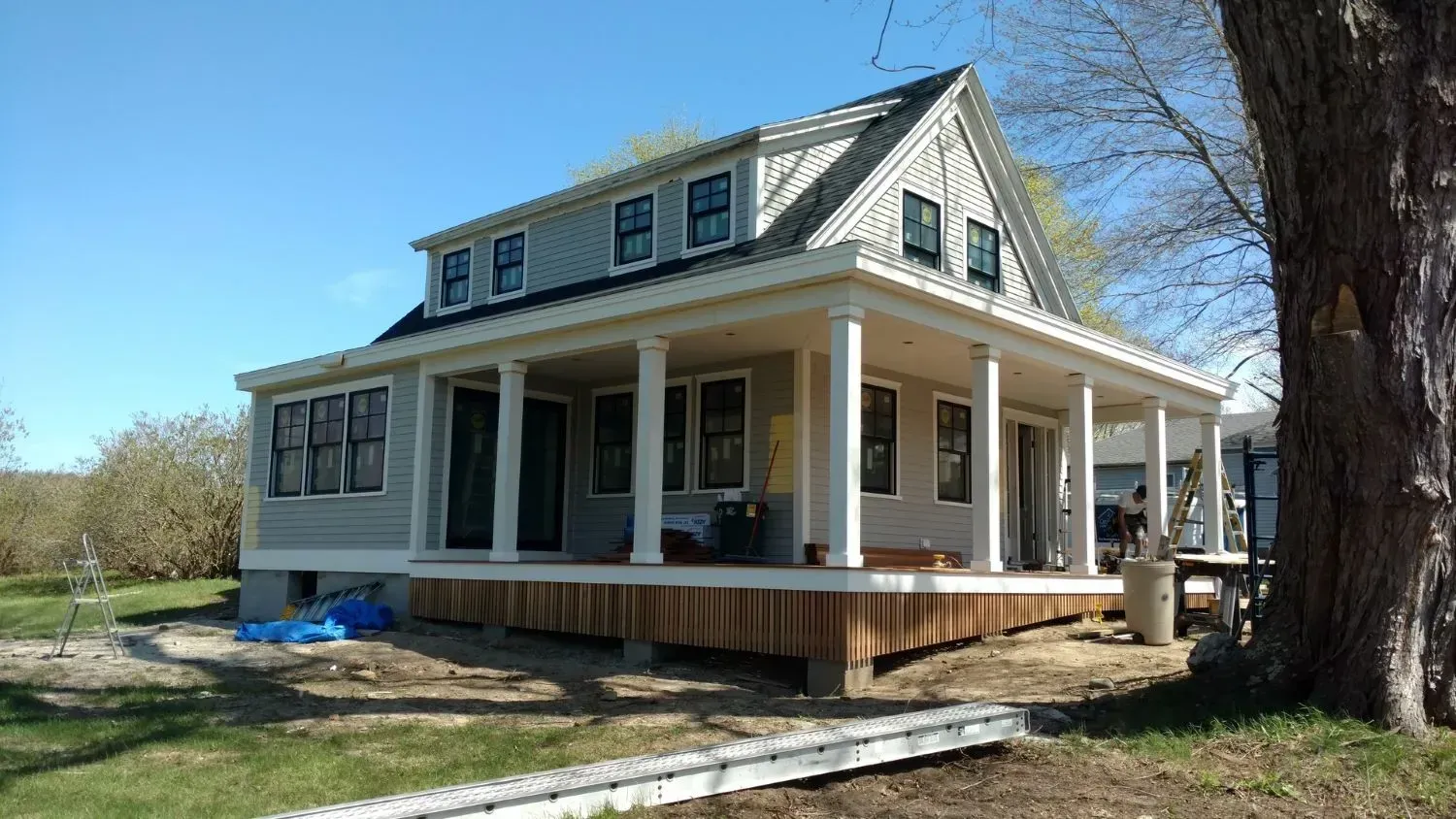 A house with a porch and a tree in front of it.