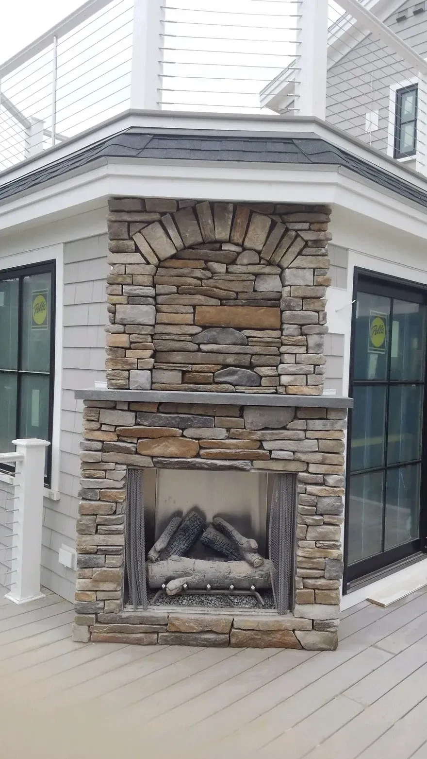 A stone fireplace is on the side of a house.