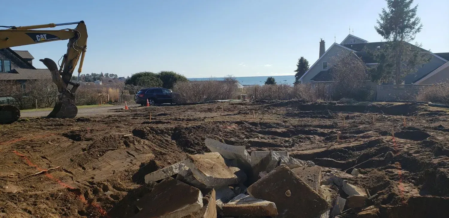 A construction site with a house in the background and a bulldozer in the foreground.
