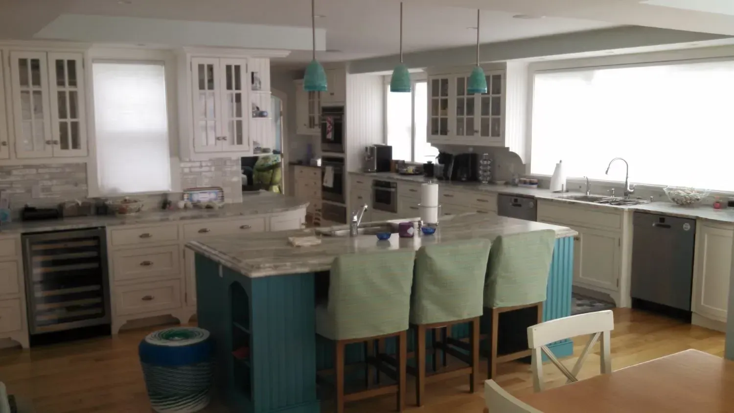 A kitchen with white cabinets and a blue island in the middle.