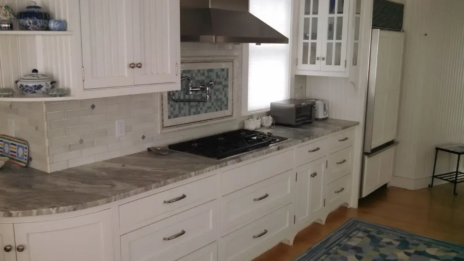 A kitchen with white cabinets , granite counter tops , a stove and a refrigerator.