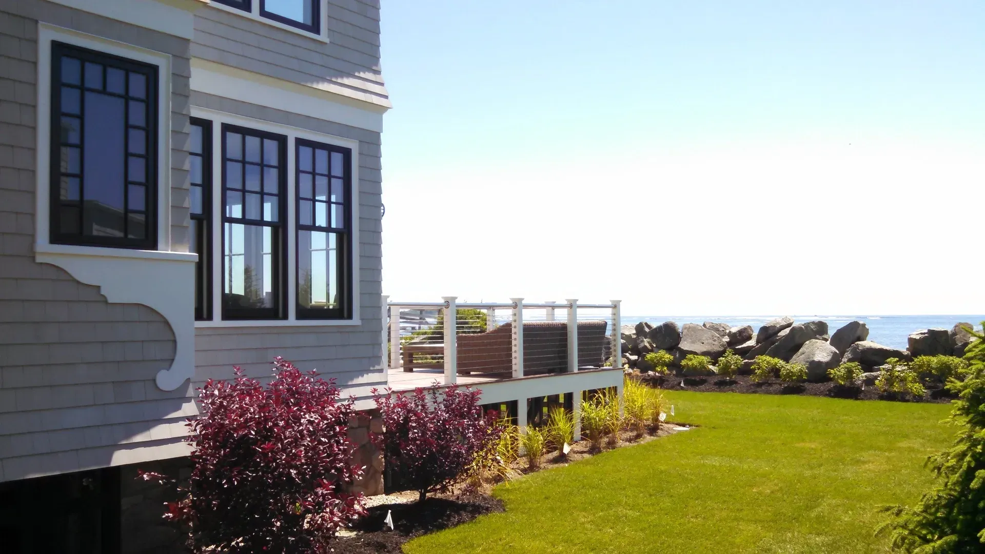 A house with a large lawn and a deck overlooking the ocean
