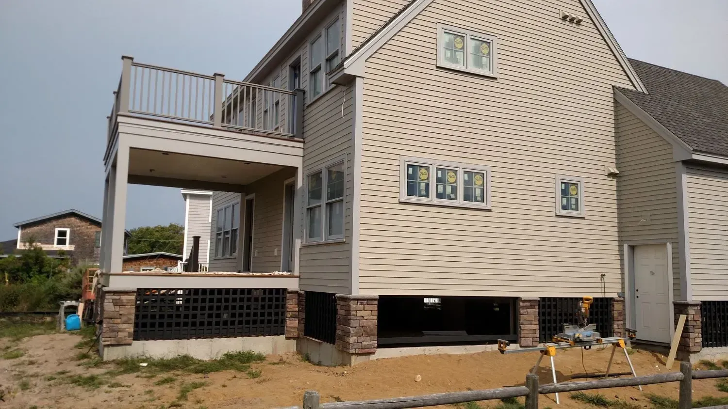 A large white house with a deck and a wooden fence in front of it.