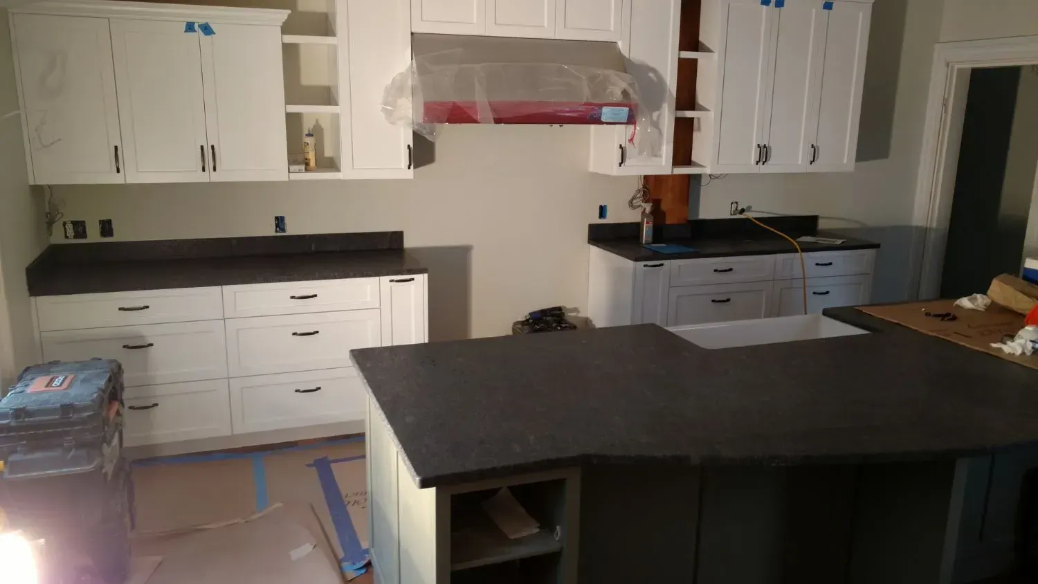 A kitchen with white cabinets and black counter tops