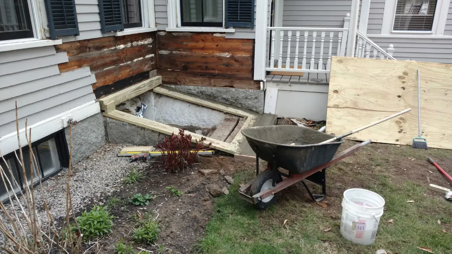 A wheelbarrow is sitting in front of a house.