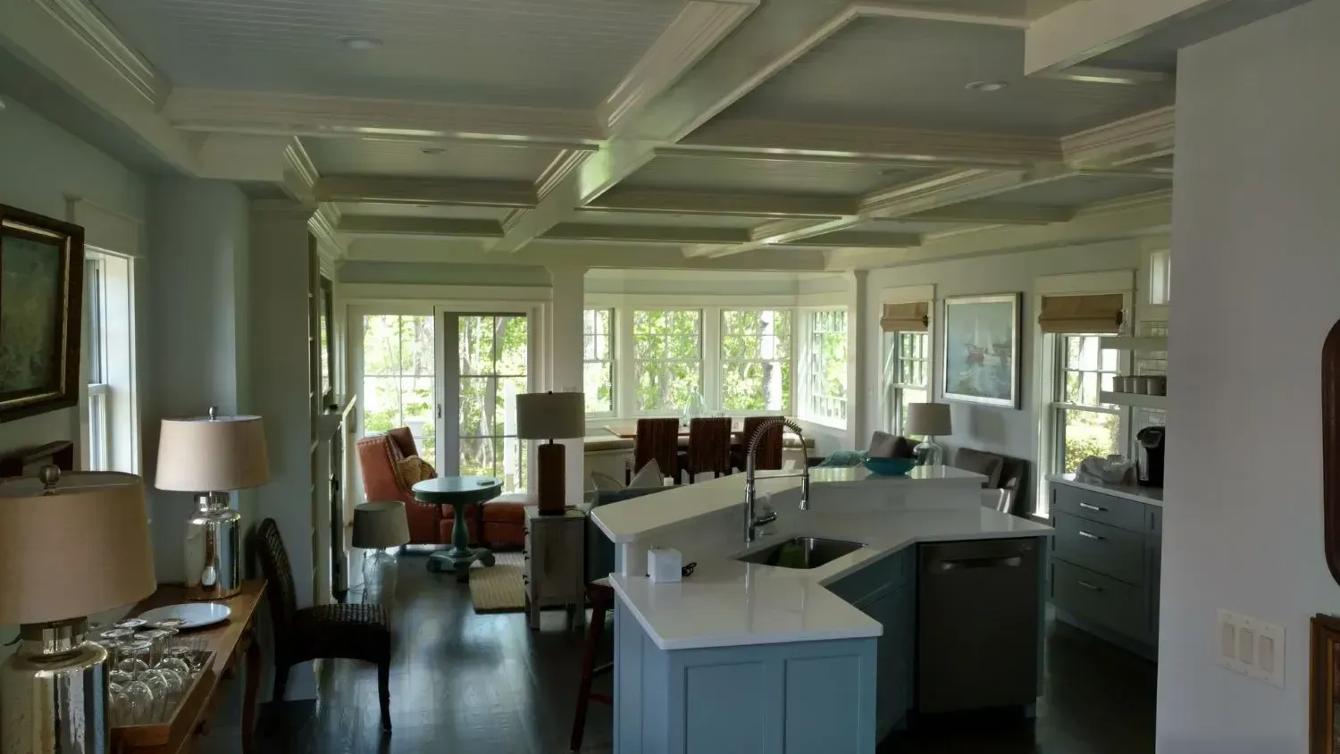 A large living room with a kitchen and a lot of windows.