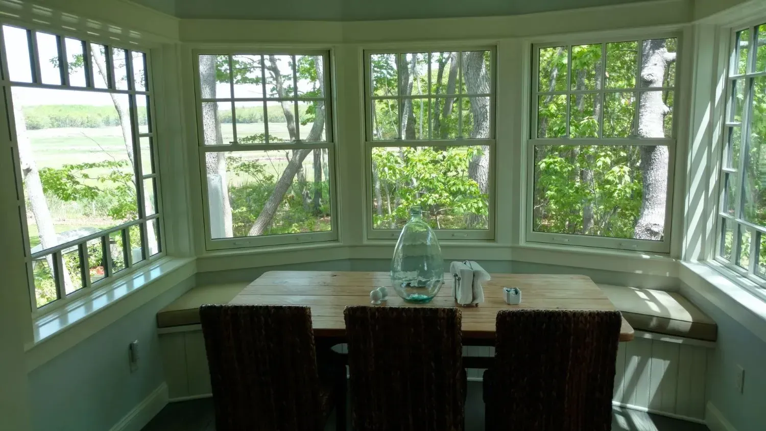 A dining room with a table and chairs and lots of windows.
