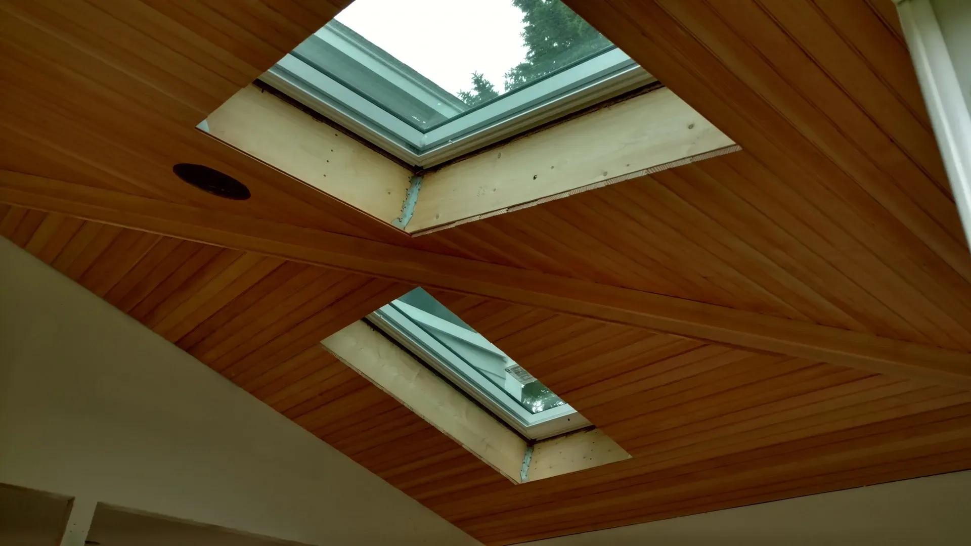 A wooden ceiling with two skylights in it