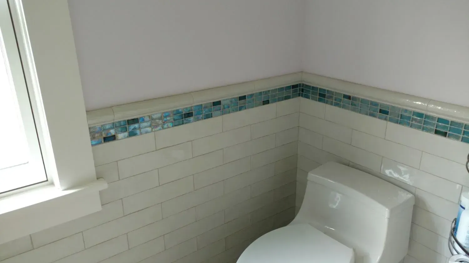 A toilet is sitting in a bathroom next to a window.