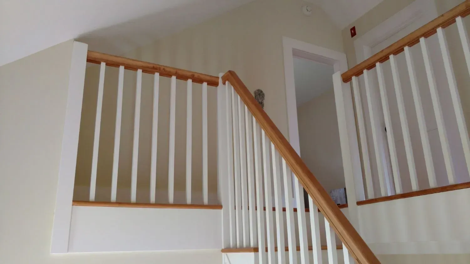 A staircase with white railings and wooden handrails in a house.