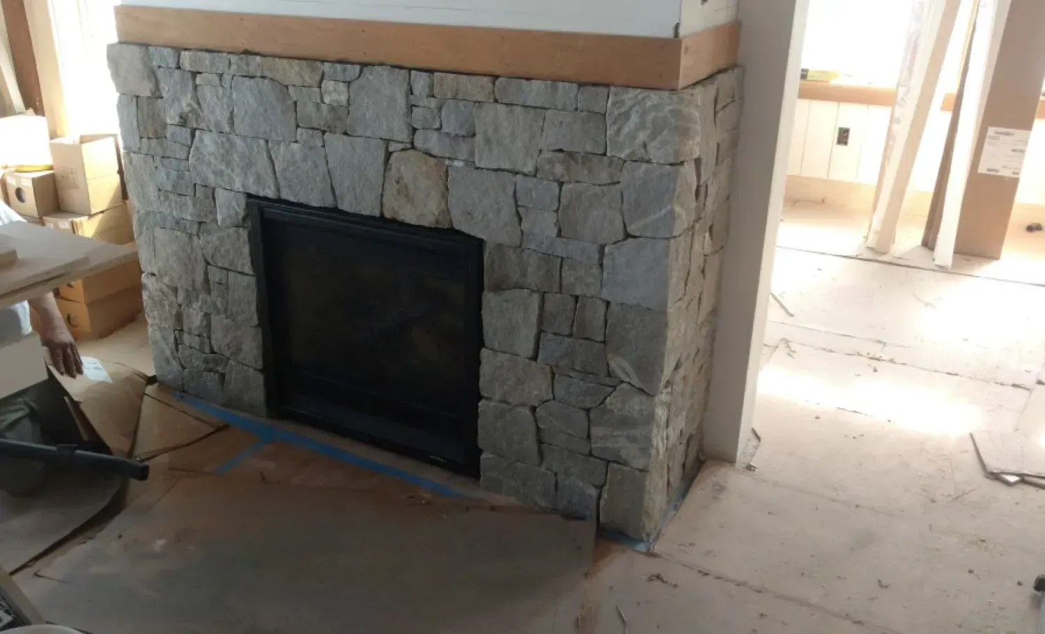 A stone fireplace is being built in a living room.