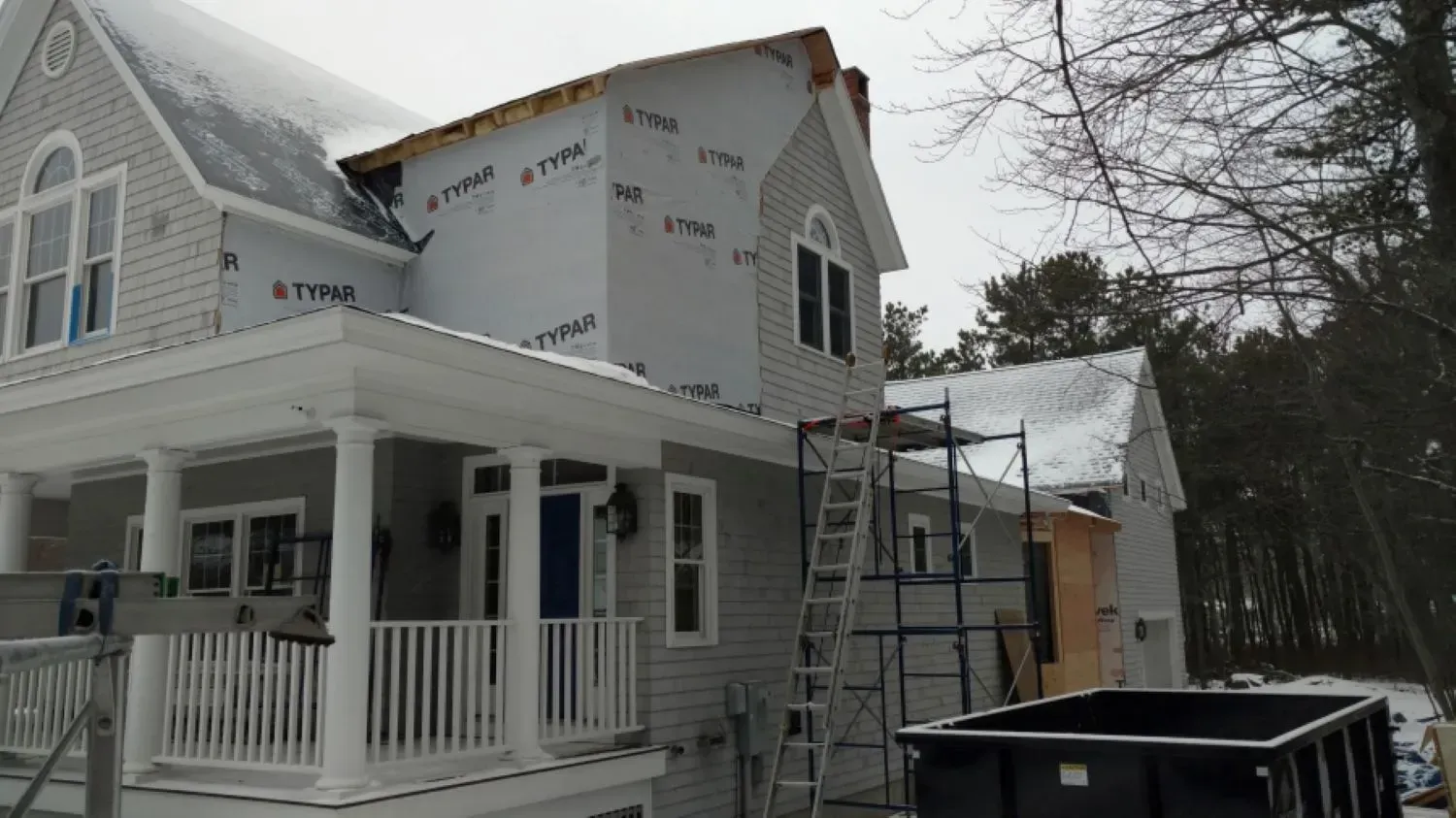A house that is being built with a dumpster in front of it.