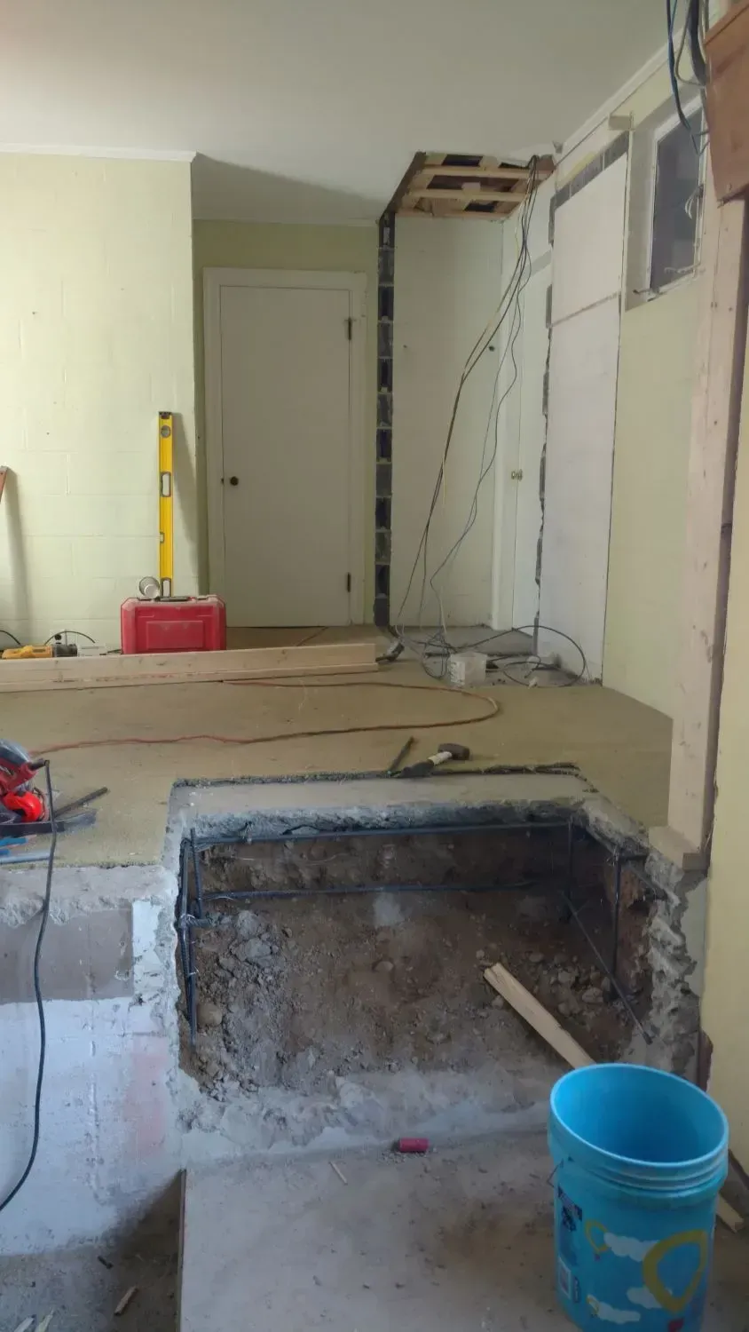 A blue bucket is sitting on the floor in a room under construction.
