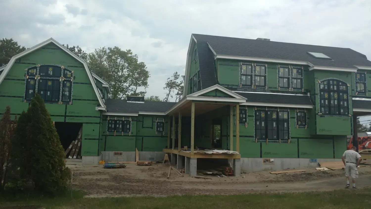 A large house under construction with green siding and a black roof