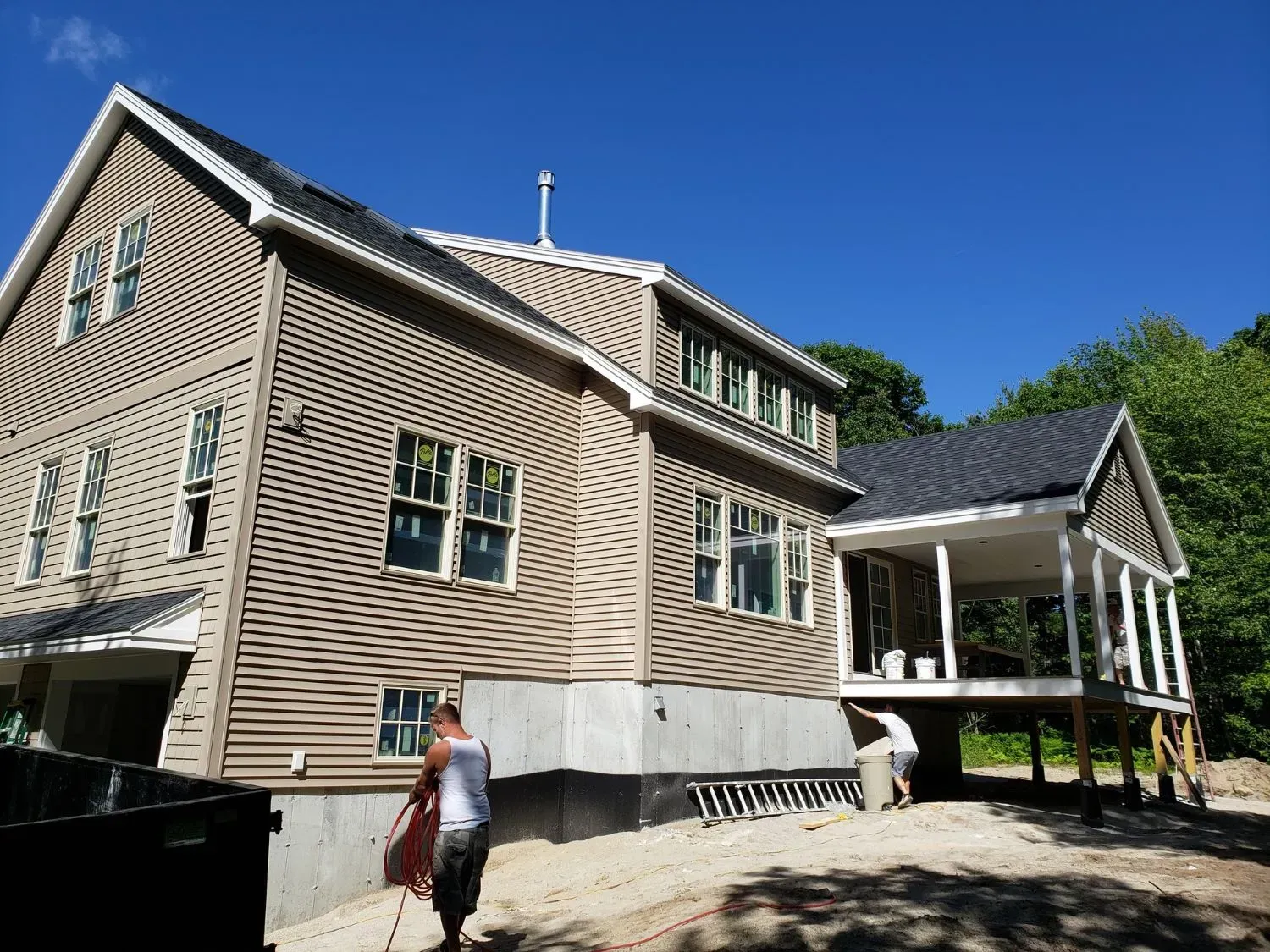 A man is standing in front of a large house under construction.