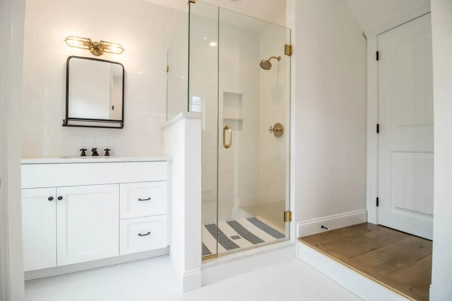 A bathroom with a walk in shower , sink and mirror.