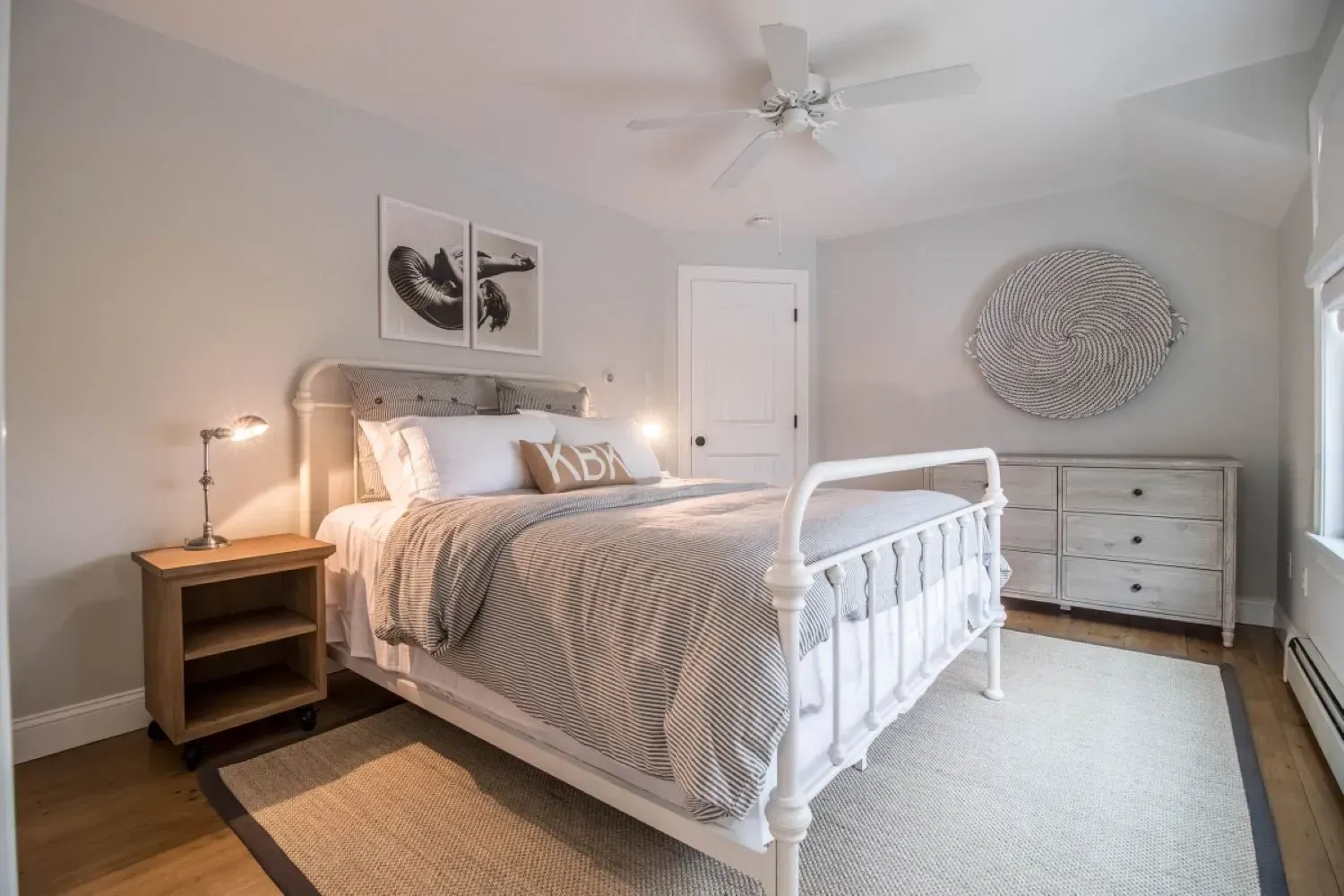A bedroom with a bed , nightstand , dresser and ceiling fan.