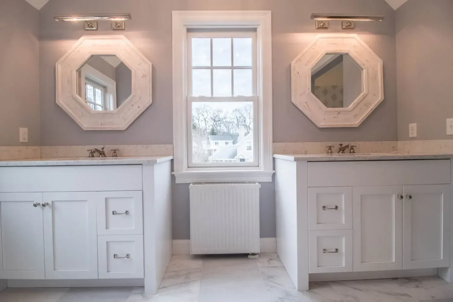 A bathroom with two sinks , two mirrors and a window.