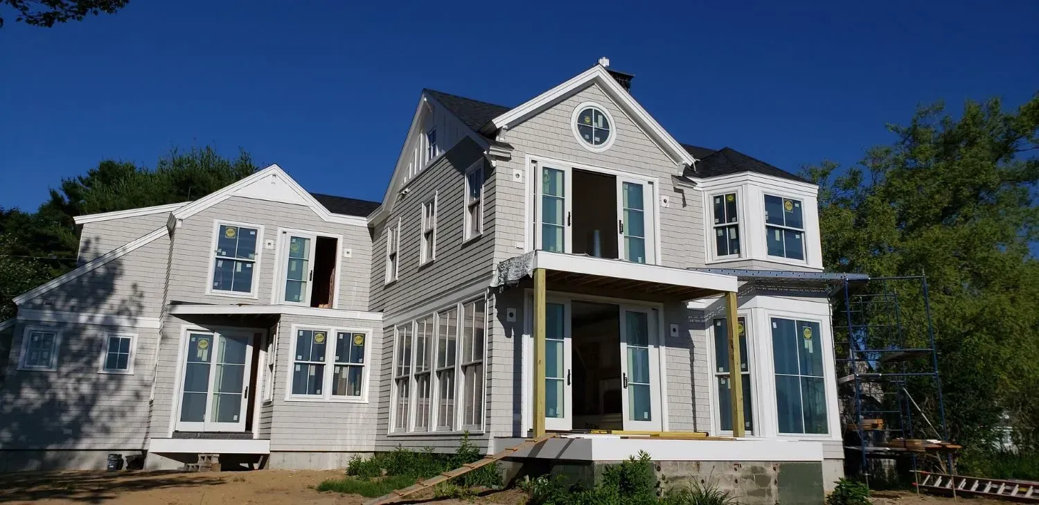 A large white house with a lot of windows is under construction.