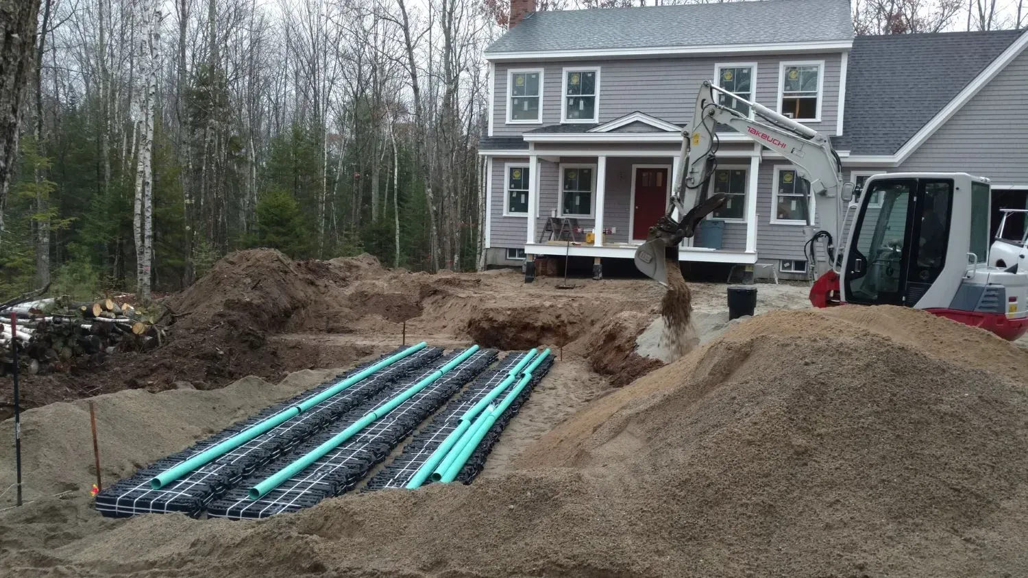 An excavator is digging a hole in front of a house.