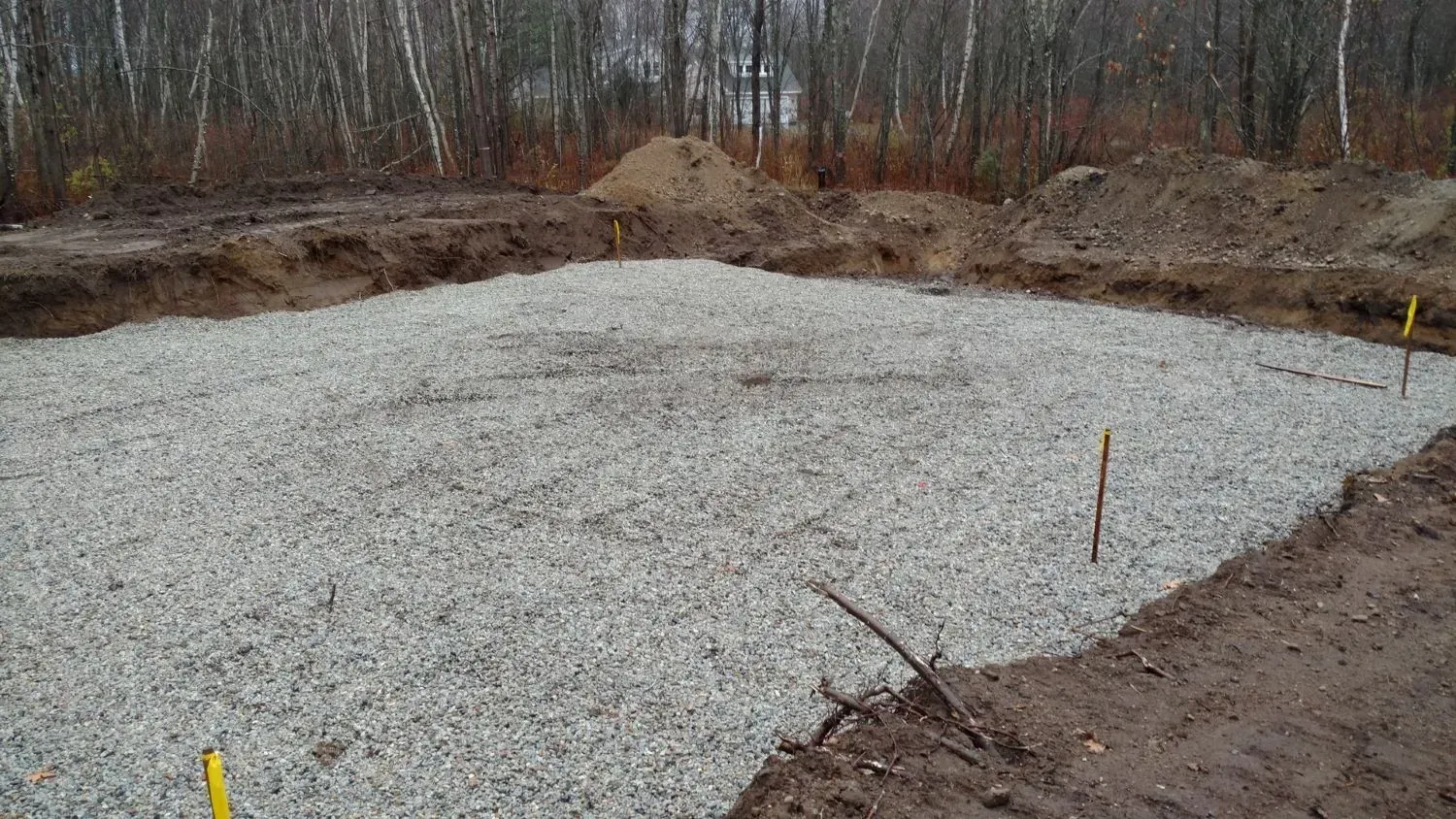 A large pile of gravel is sitting in the middle of a dirt field.