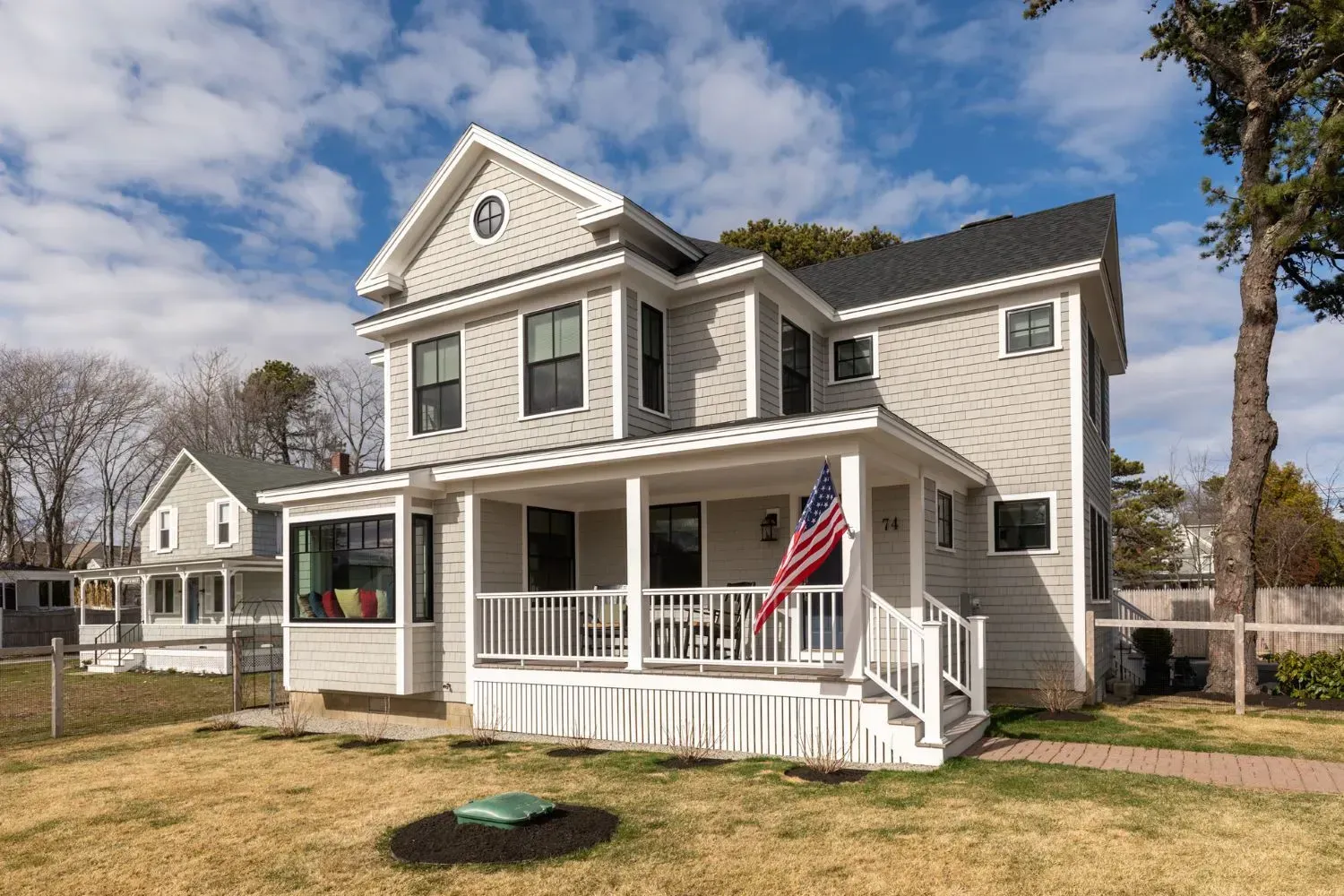A large white house with a large porch and an american flag on it.