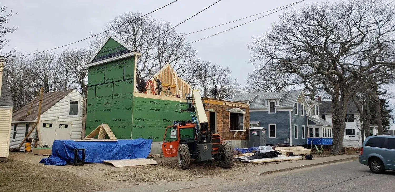A tractor is parked in front of a house under construction.