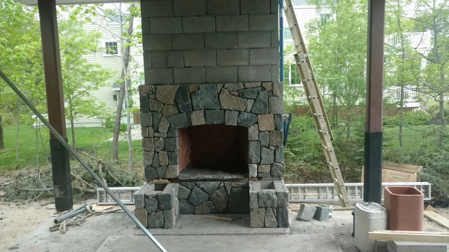 A stone fireplace is being built under a canopy