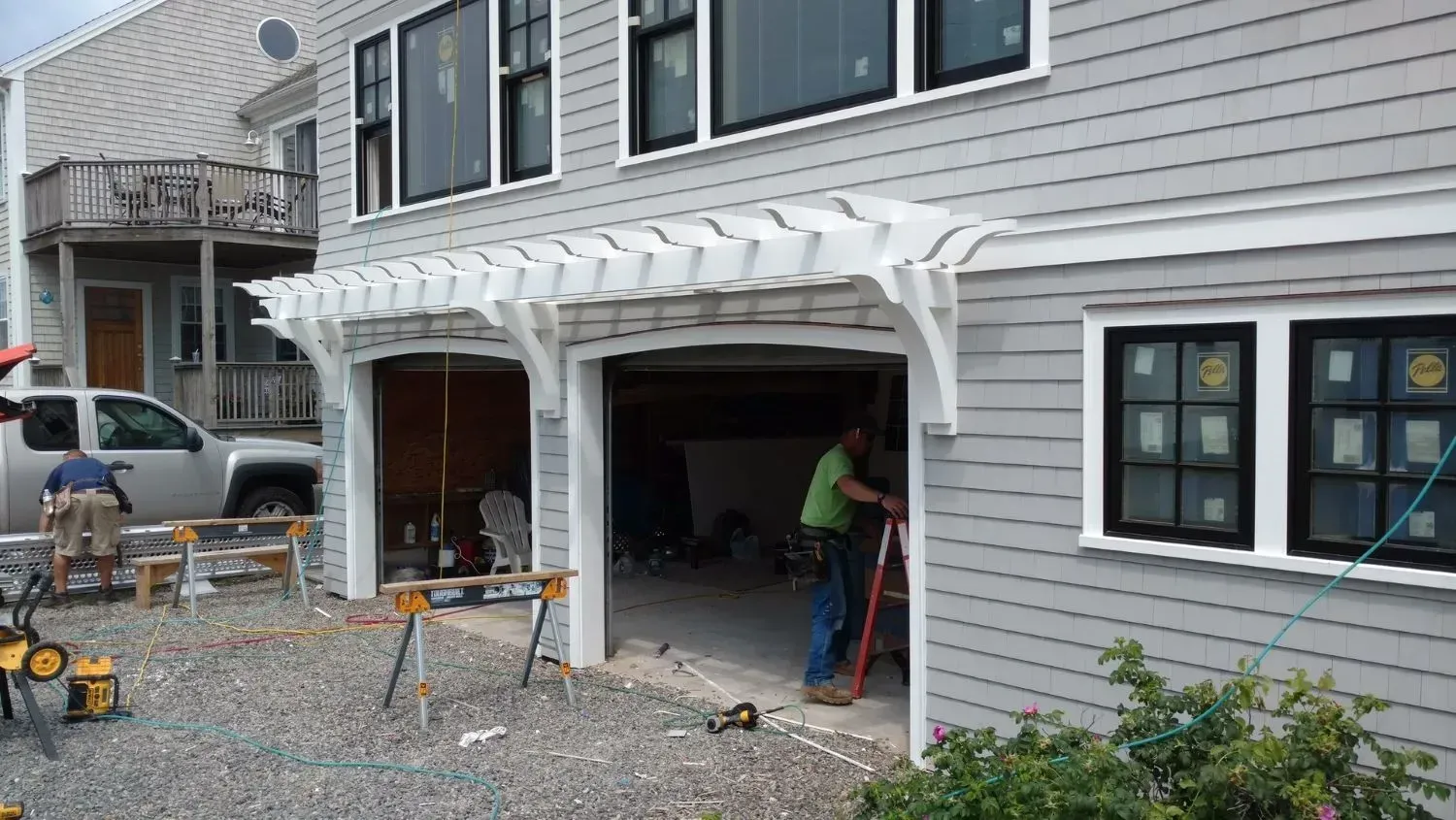 A man is working on a pergola over a garage door.