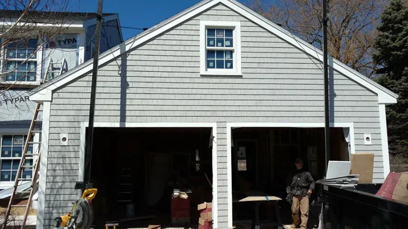 A man is standing in front of a garage that is being remodeled