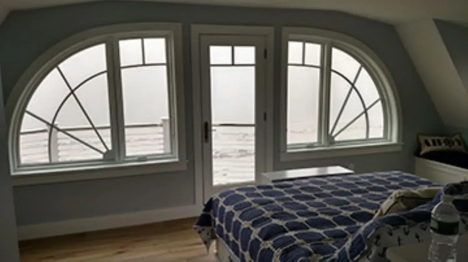 A bedroom with a bed and a balcony with a view of the ocean.