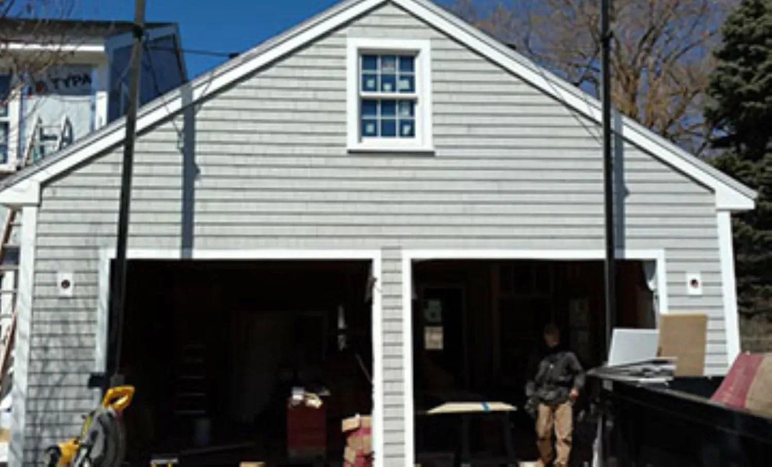 A man is standing in front of a garage with the door open