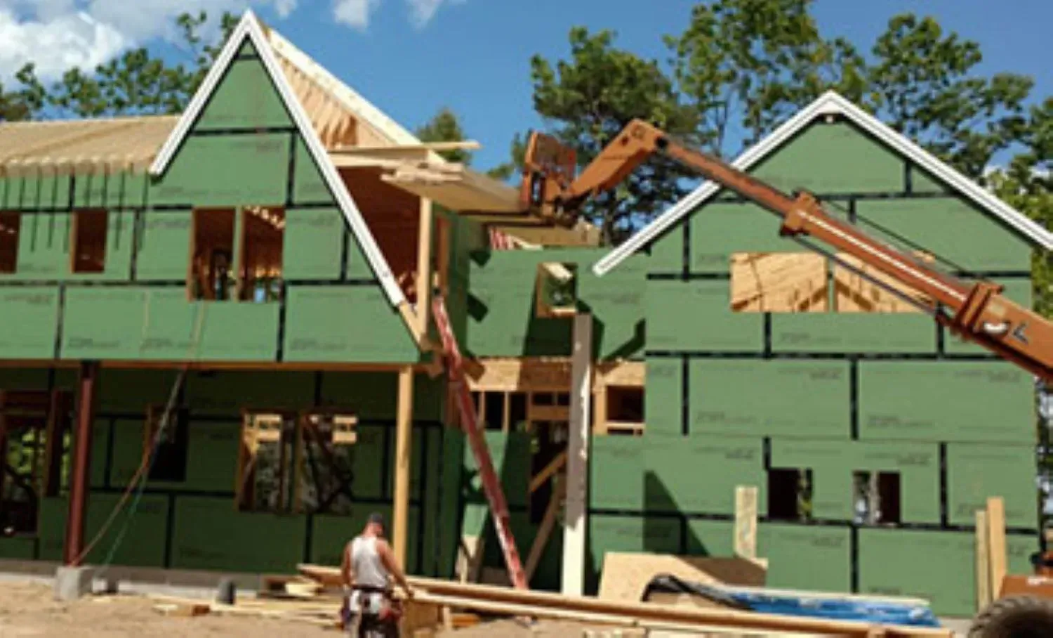 A man is standing in front of a house under construction.