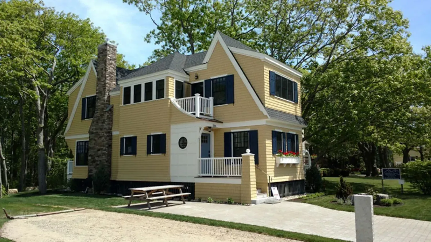 A large yellow house with a picnic table in front of it