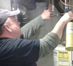 A man is working on a water heater with a screwdriver.