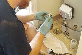 A man wearing blue gloves is working on a water heater.