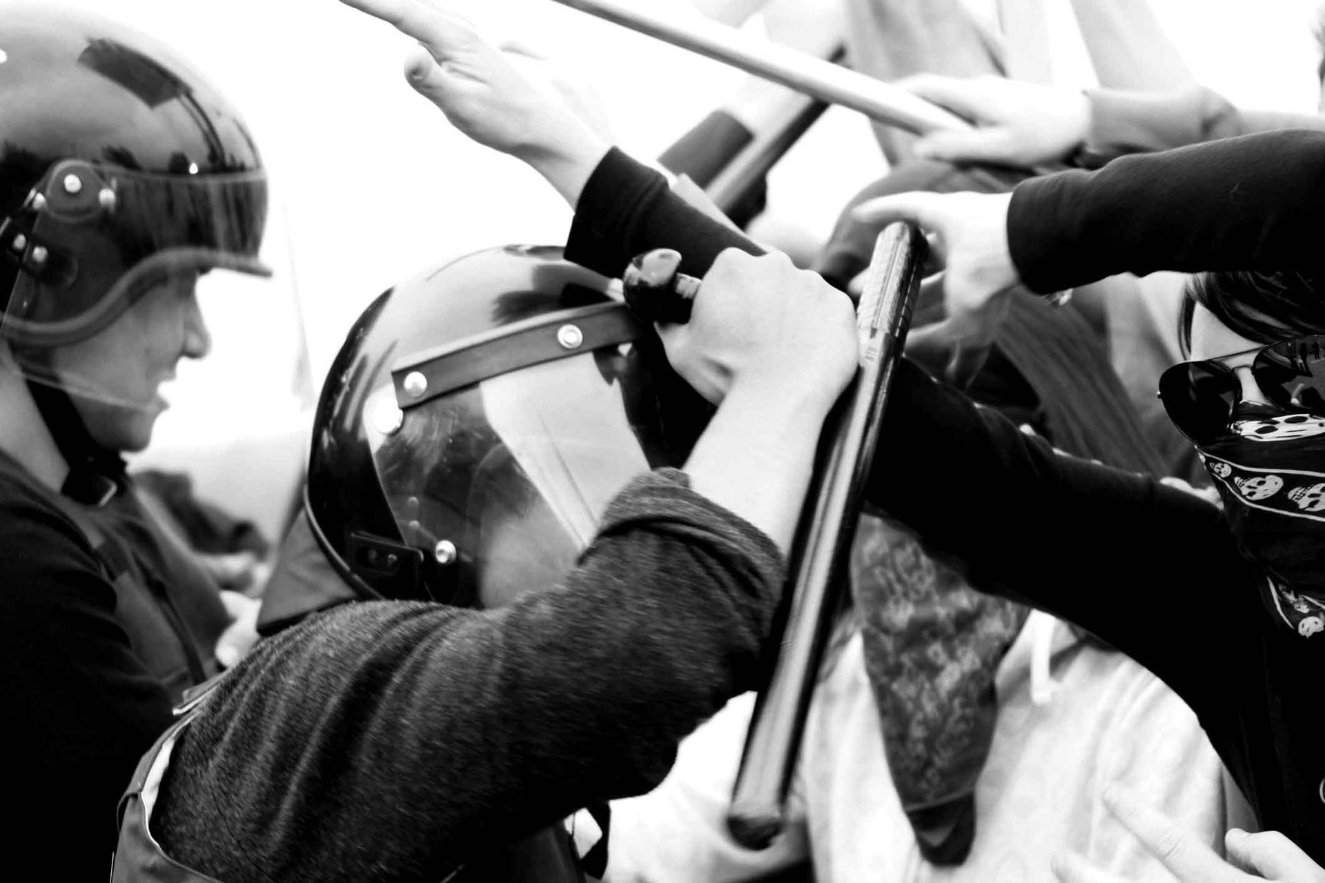 A black and white photo of a man wearing a helmet holding a baton